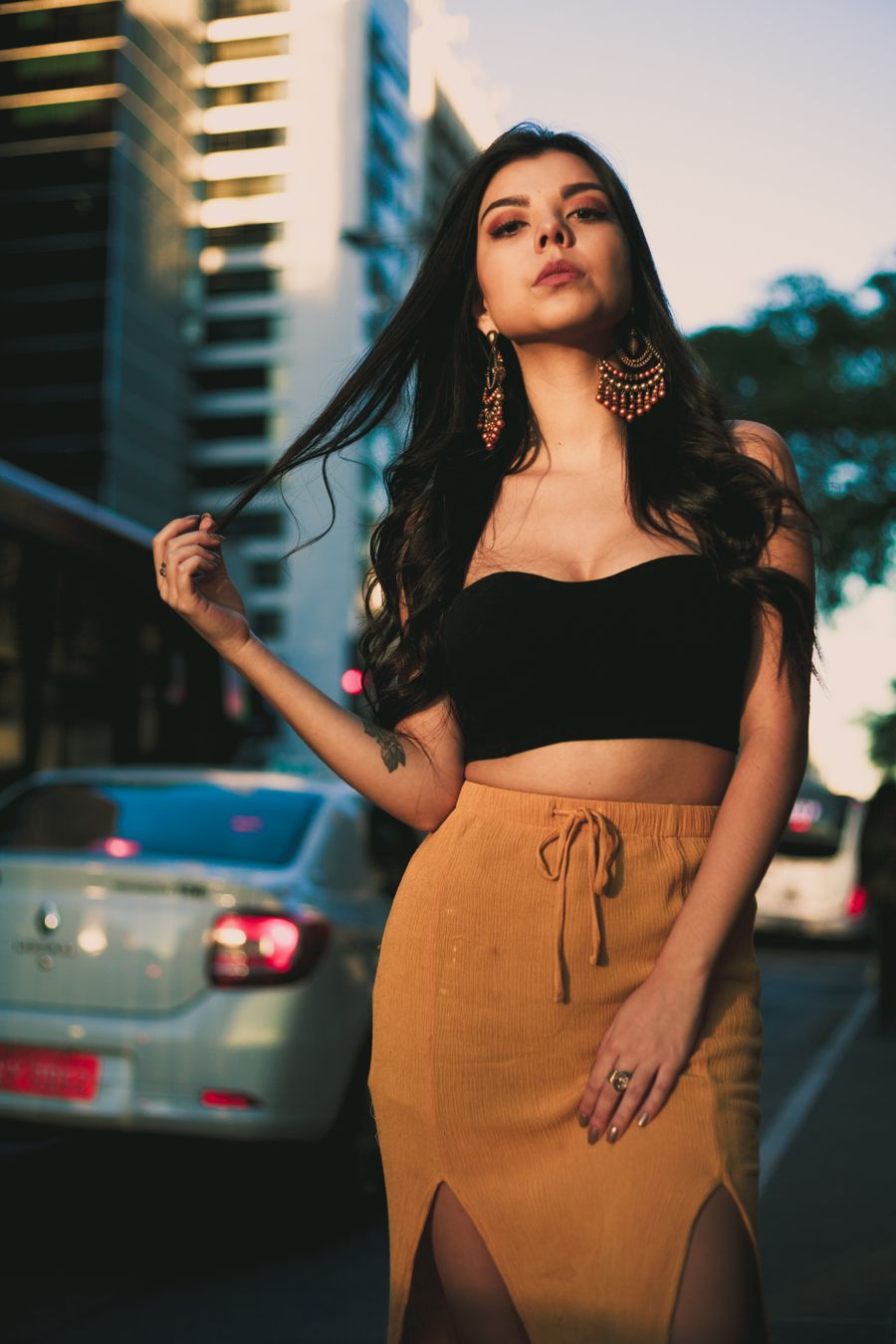 Young woman in a black strapless top and mustard skirt on a city street at sunset